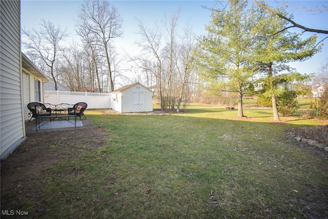 view of yard with an outbuilding, a patio area, a storage unit, and fence