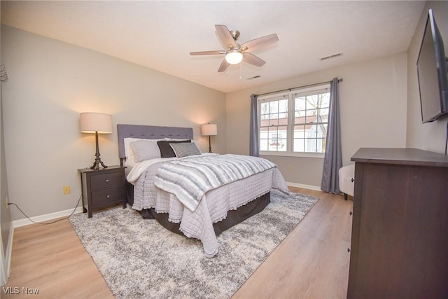 bedroom with a ceiling fan, baseboards, visible vents, and light wood finished floors