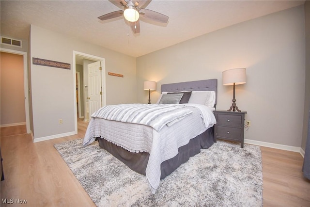 bedroom with visible vents, a ceiling fan, baseboards, and wood finished floors