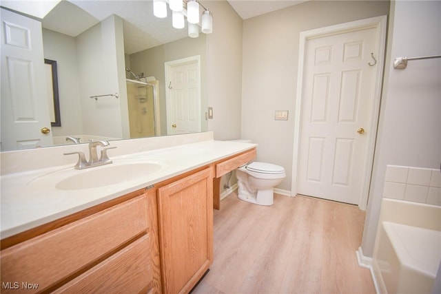 bathroom with vanity, wood finished floors, a shower stall, a garden tub, and toilet