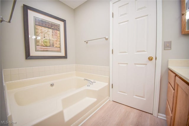 bathroom with wood finished floors, a bath, and vanity