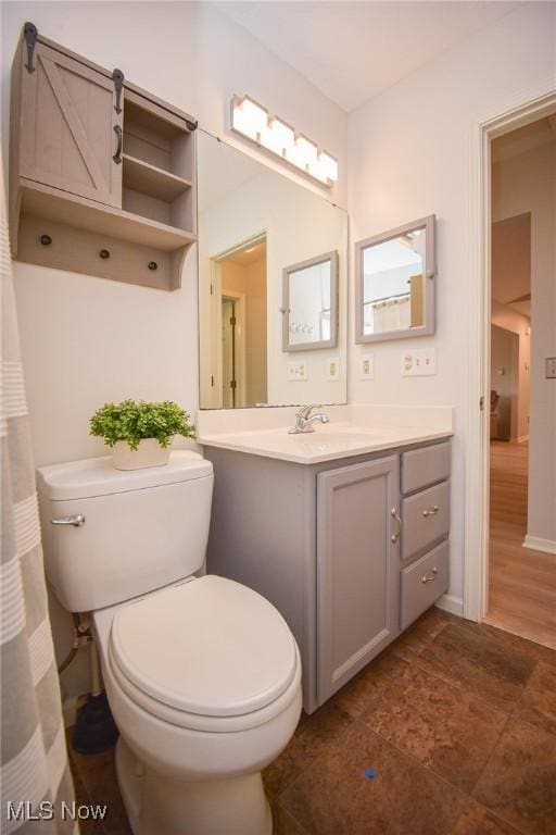 full bathroom with toilet, vanity, and baseboards