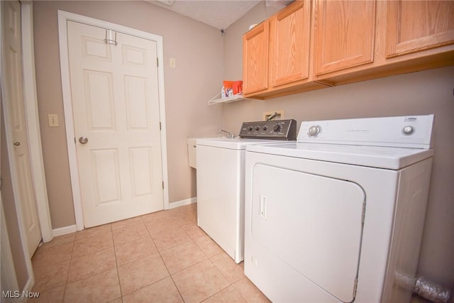 laundry area featuring baseboards, cabinet space, separate washer and dryer, and light tile patterned flooring