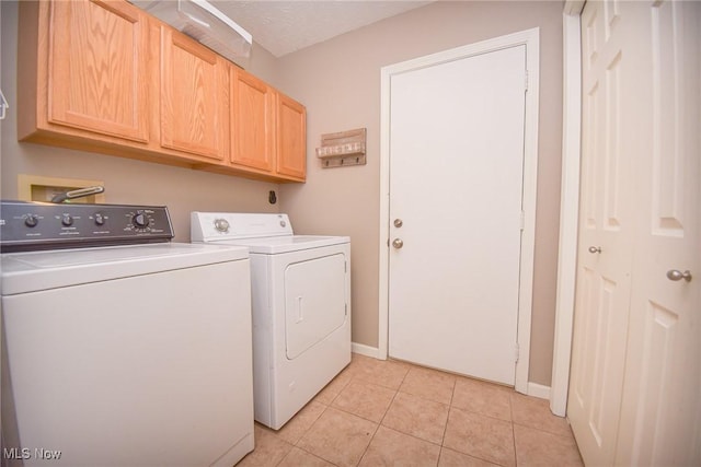 washroom with light tile patterned floors, baseboards, cabinet space, and washing machine and clothes dryer