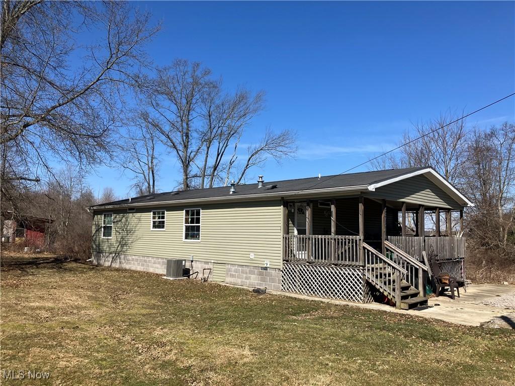 back of property with central AC unit, a lawn, and a porch