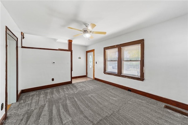 carpeted spare room with visible vents, baseboards, and ceiling fan