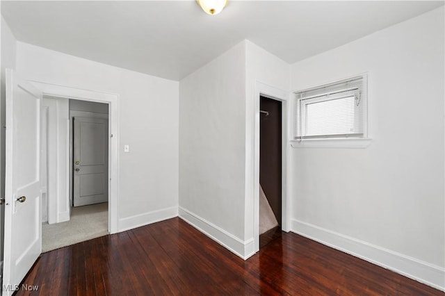 unfurnished bedroom featuring a closet, wood-type flooring, and baseboards