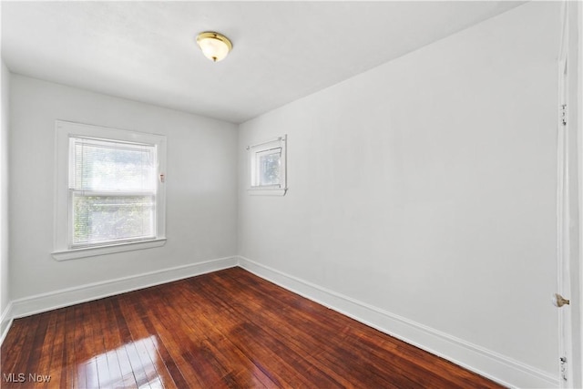 spare room with dark wood finished floors, baseboards, and a wealth of natural light