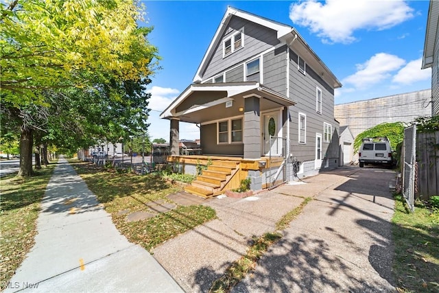 traditional style home featuring an outbuilding, covered porch, driveway, and fence