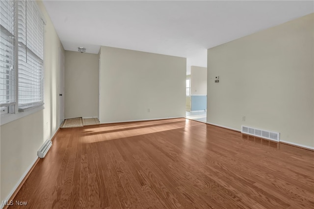 unfurnished room featuring visible vents, baseboards, and wood finished floors