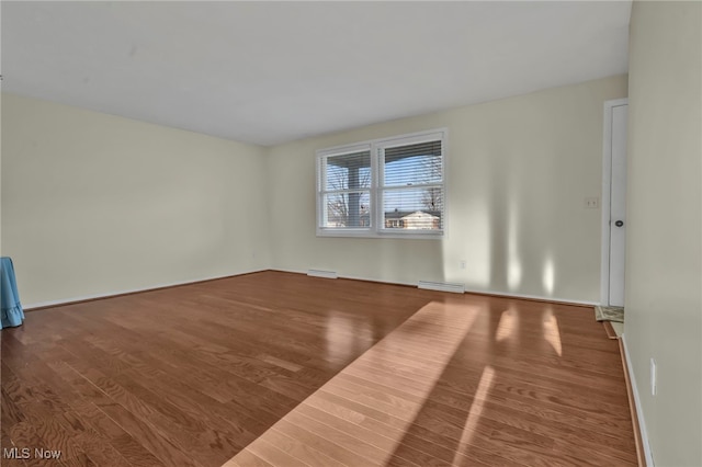 empty room featuring visible vents, baseboards, and wood finished floors