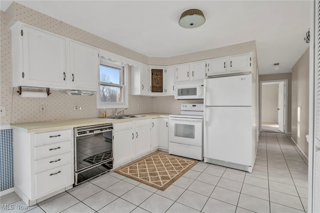 kitchen with white appliances, wallpapered walls, light tile patterned flooring, a sink, and light countertops