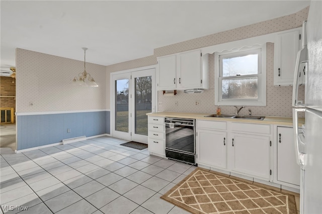 kitchen featuring a wainscoted wall, white cabinetry, dishwasher, and wallpapered walls