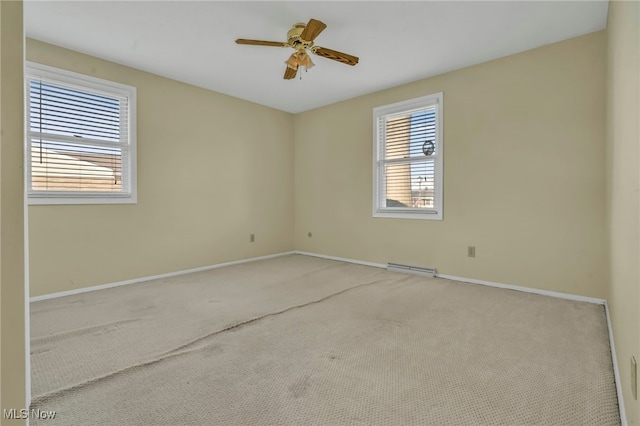 carpeted empty room featuring baseboards and ceiling fan