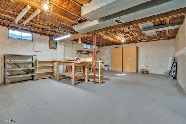 basement featuring a workshop area, electric panel, and visible vents