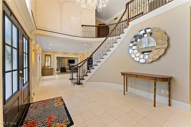 entryway with stairway, baseboards, ornamental molding, tile patterned flooring, and a towering ceiling