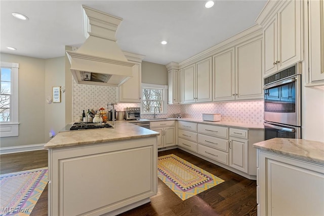 kitchen with dark wood finished floors, tasteful backsplash, custom range hood, and a sink