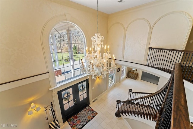 foyer with a notable chandelier, french doors, visible vents, and a towering ceiling