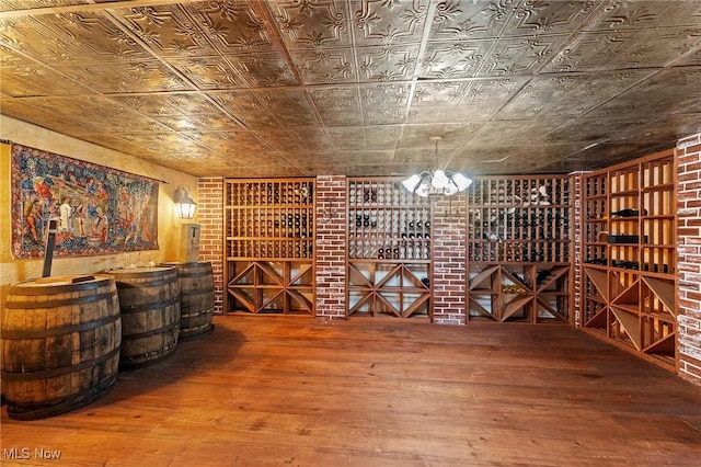 wine cellar featuring brick wall, wood-type flooring, and an ornate ceiling