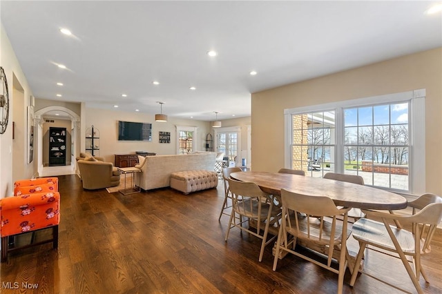 dining room featuring arched walkways, recessed lighting, and dark wood-style flooring