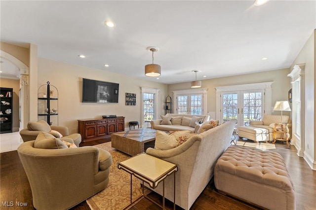 living area with wood finished floors, recessed lighting, french doors, and arched walkways