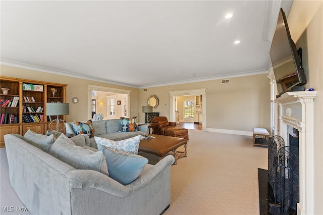 living room featuring visible vents, a fireplace with flush hearth, ornamental molding, carpet flooring, and baseboards