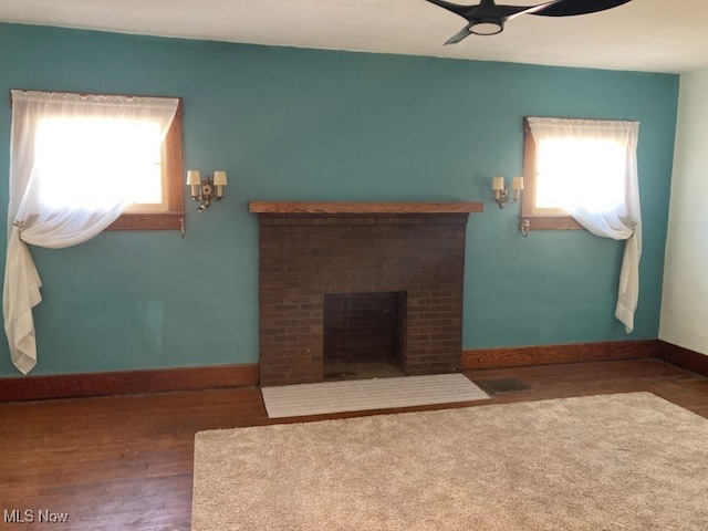 living room featuring visible vents, a brick fireplace, ceiling fan, baseboards, and wood finished floors