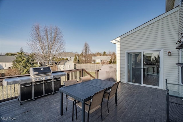 wooden terrace with an outbuilding, outdoor dining space, a shed, and grilling area