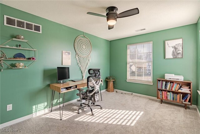 carpeted home office with a ceiling fan, baseboards, and visible vents