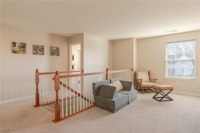 living area featuring an upstairs landing, carpet flooring, visible vents, and baseboards