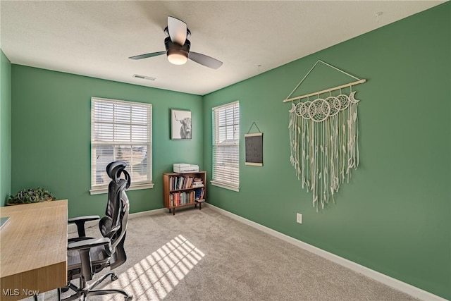 carpeted office space featuring visible vents, ceiling fan, and baseboards