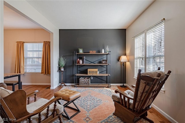 living area with a wealth of natural light, baseboards, and wood finished floors