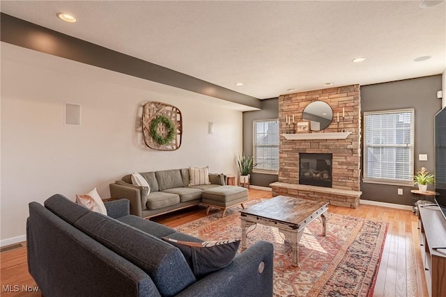 living area with visible vents, a fireplace, light wood-type flooring, and baseboards