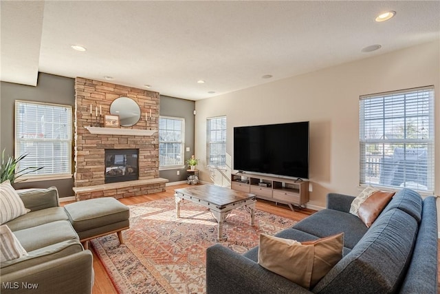 living room featuring a fireplace, baseboards, and wood finished floors