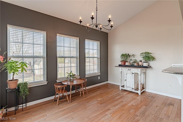 dining space featuring baseboards, an inviting chandelier, light wood-style flooring, and vaulted ceiling