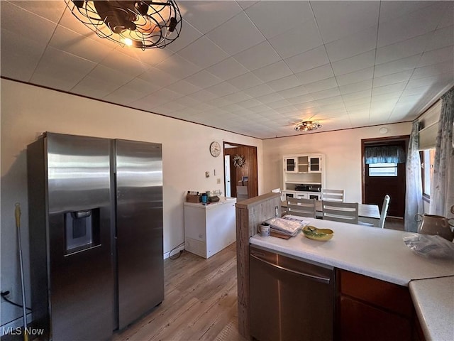 kitchen featuring stainless steel appliances, dark brown cabinets, wood finished floors, and light countertops