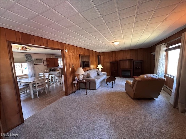 living room featuring a wealth of natural light, carpet, a baseboard heating unit, and a wall unit AC