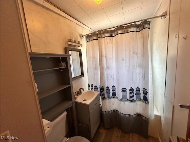 full bath with wood walls, toilet, shower / tub combo with curtain, wood finished floors, and vanity