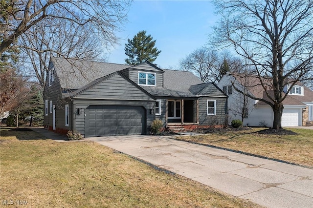 traditional home featuring a front lawn, a garage, driveway, and a shingled roof