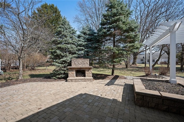 view of patio with an outdoor stone fireplace and a pergola