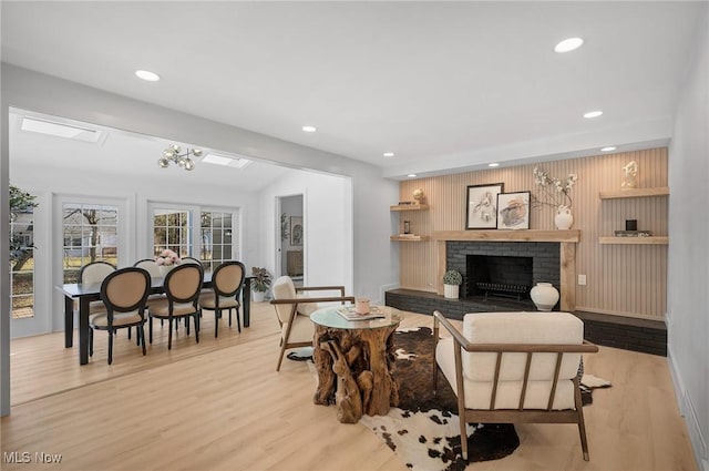 living room with recessed lighting, light wood-type flooring, a fireplace, and vaulted ceiling