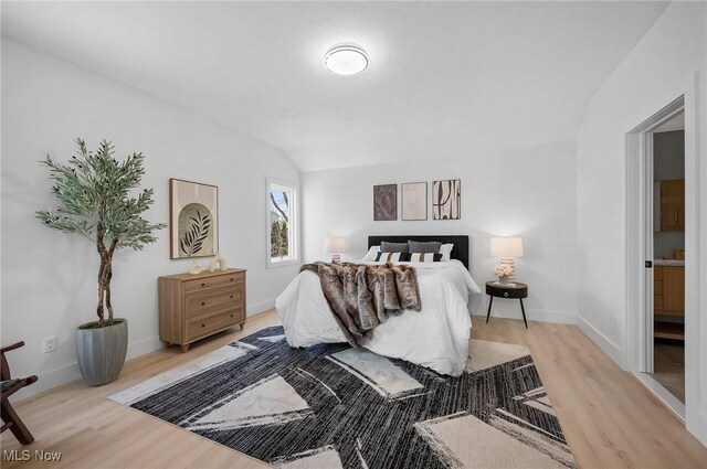 bedroom featuring light wood-type flooring, baseboards, and vaulted ceiling