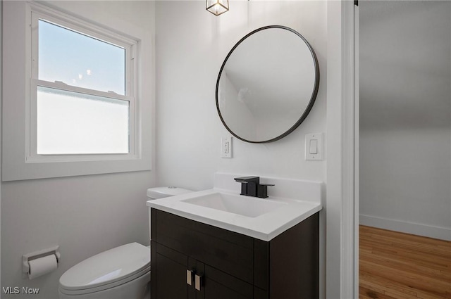 bathroom featuring baseboards, toilet, wood finished floors, and vanity