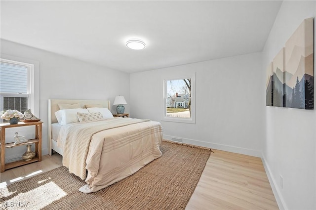 bedroom with light wood-type flooring, visible vents, and baseboards