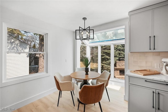 dining space featuring an inviting chandelier, baseboards, and light wood finished floors