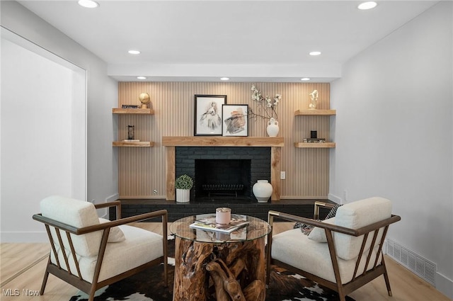 living room with recessed lighting, visible vents, a brick fireplace, and wood finished floors