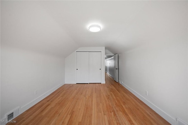 bonus room with visible vents, lofted ceiling, baseboards, and light wood-style flooring