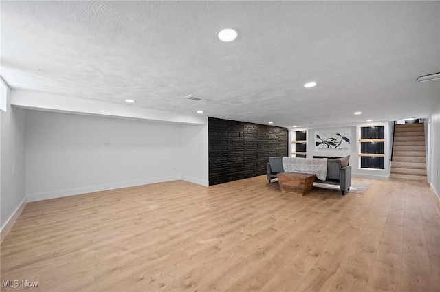 unfurnished room with built in shelves, visible vents, stairs, a textured ceiling, and light wood-type flooring