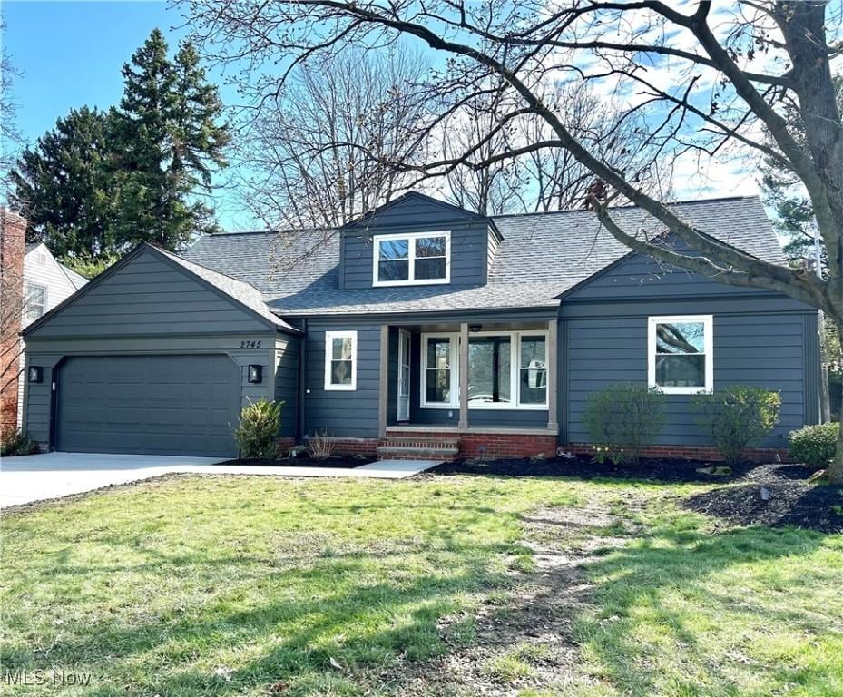 view of front facade with an attached garage, a shingled roof, concrete driveway, and a front yard