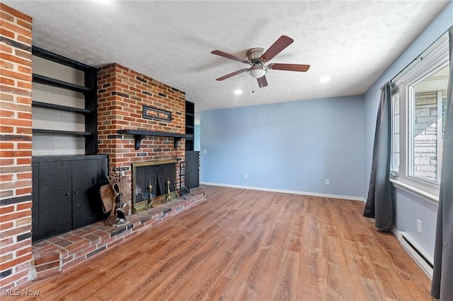 unfurnished living room featuring baseboards, light wood-type flooring, baseboard heating, and a textured ceiling